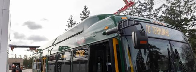 An electric bus owned by King County Metro connects to an overhead pantograph for charging. (Photo courtesy of King County Metro)