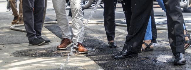 New York City Department of Environmental Protection Commissioner Rohit T. Aggarwala, right, sprays water onto a porous pavement section in Brooklyn. (Image courtesy of New York City Department of Environmental Protection via Flickr)  